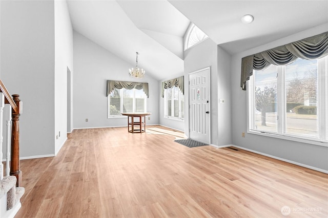 foyer entrance with lofted ceiling, a notable chandelier, and light wood-type flooring