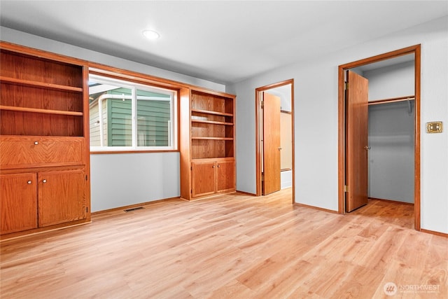 unfurnished bedroom featuring a spacious closet, light hardwood / wood-style floors, and a closet