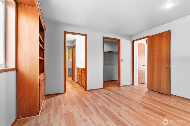 unfurnished bedroom featuring a closet, a spacious closet, and light hardwood / wood-style flooring