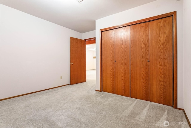 unfurnished bedroom with light colored carpet and a closet