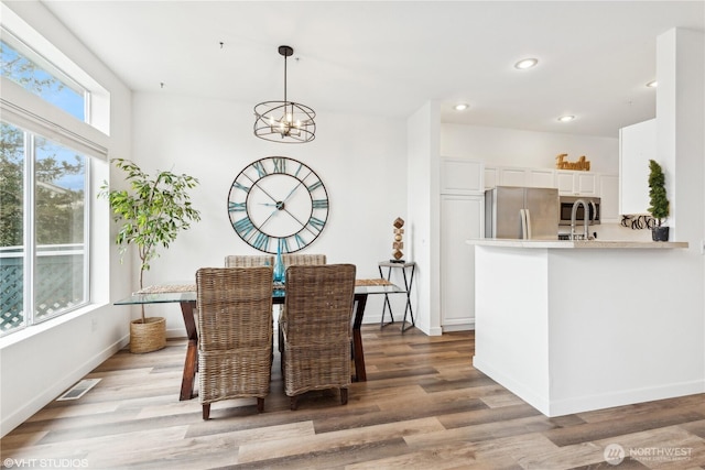 dining space with light wood-type flooring, an inviting chandelier, and sink