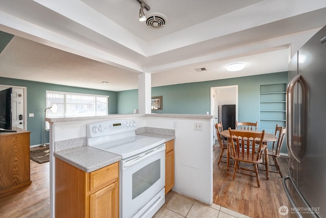 kitchen featuring stainless steel refrigerator, white electric stove, kitchen peninsula, and light wood-type flooring