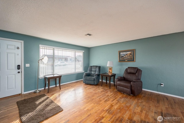 living area with hardwood / wood-style flooring and a textured ceiling