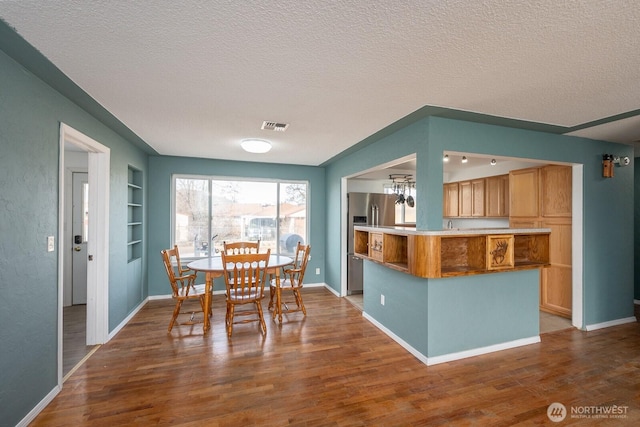 unfurnished dining area with hardwood / wood-style floors, built in features, and a textured ceiling