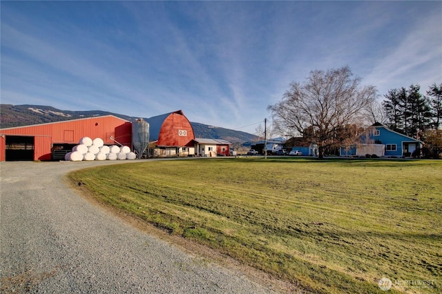 view of front facade featuring a mountain view, an outbuilding, and a front yard