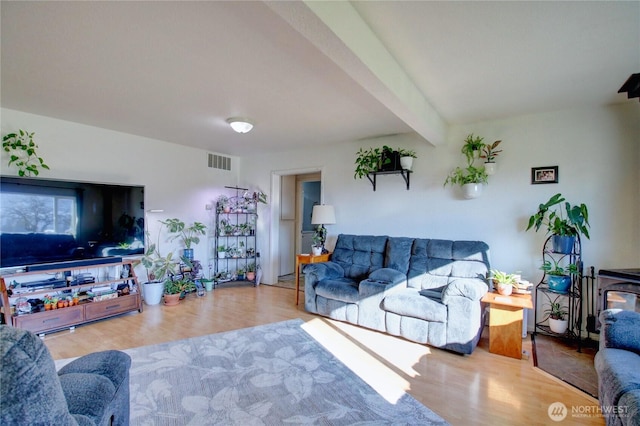 living room with beam ceiling, visible vents, and wood finished floors