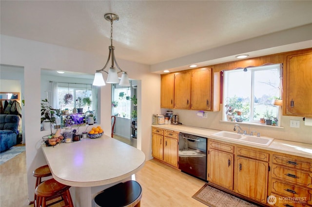 kitchen featuring black dishwasher, hanging light fixtures, a sink, light countertops, and a wealth of natural light