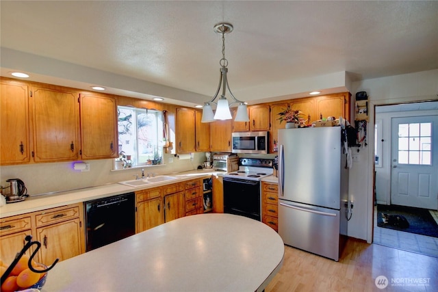 kitchen with stainless steel appliances, a sink, light countertops, brown cabinets, and pendant lighting