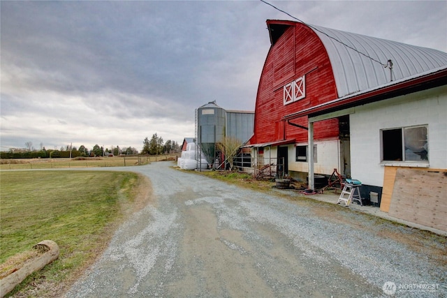 exterior space featuring a barn, a lawn, a gambrel roof, metal roof, and an outbuilding