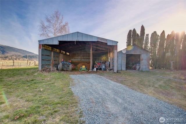 view of pole building with driveway, a lawn, and a mountain view