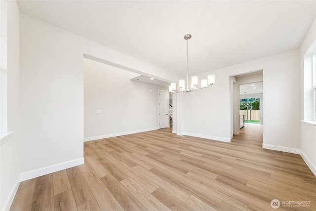 unfurnished dining area featuring a notable chandelier and light wood-type flooring