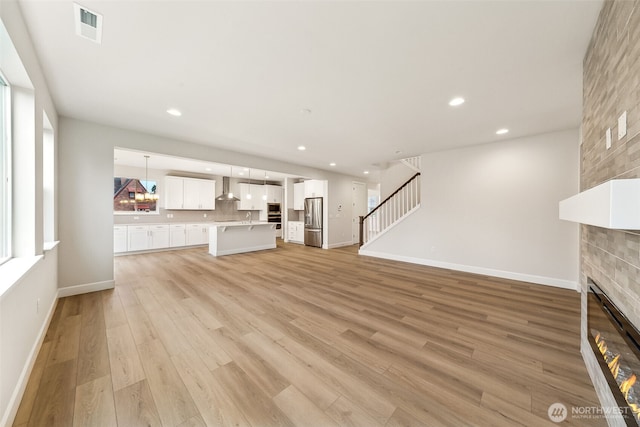 unfurnished living room with a fireplace, sink, and light hardwood / wood-style flooring