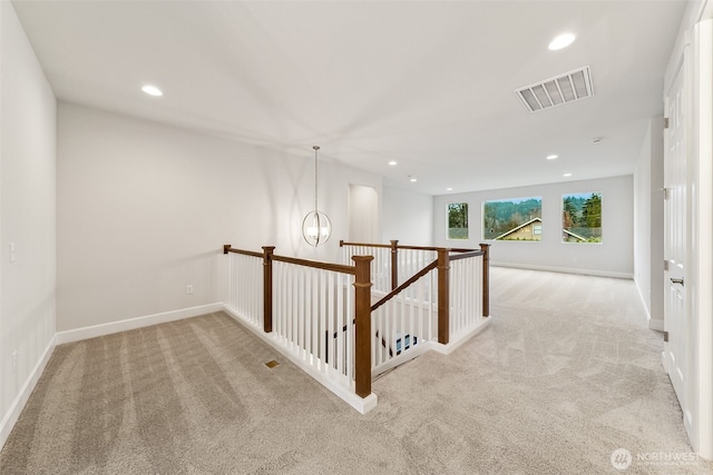 corridor with light colored carpet and a chandelier