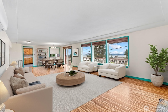 living area with light wood-style flooring, baseboards, and an inviting chandelier