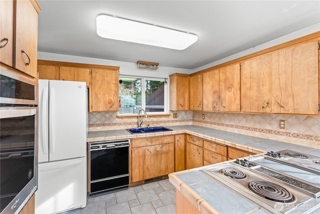 kitchen with a sink, black dishwasher, tile counters, range, and freestanding refrigerator