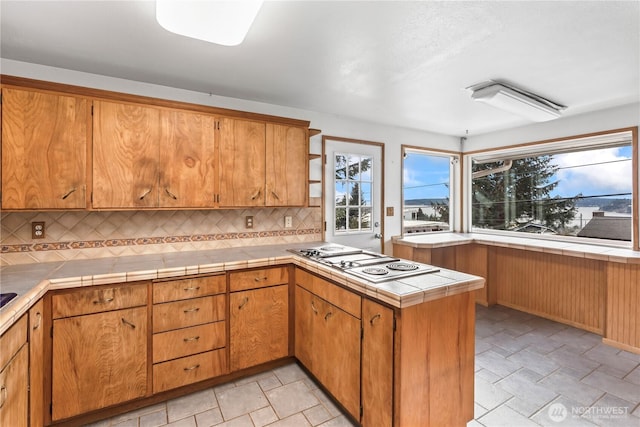 kitchen with tile counters, brown cabinets, and stainless steel gas stovetop