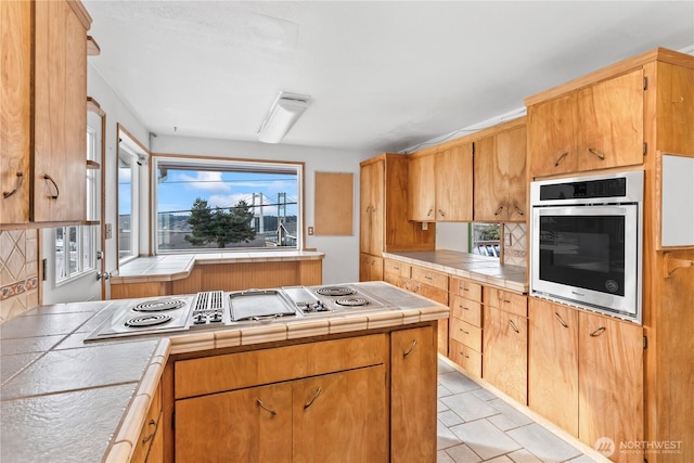 kitchen featuring appliances with stainless steel finishes, brown cabinetry, and tile counters