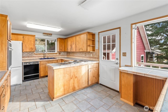 kitchen with black dishwasher, tile counters, stainless steel gas stovetop, open shelves, and a sink