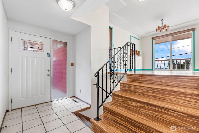 entrance foyer with baseboards, light tile patterned floors, an inviting chandelier, and stairs