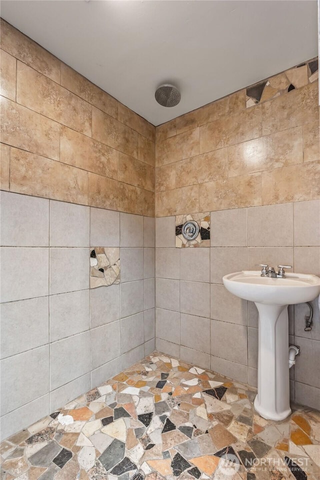 bathroom with tiled shower and tile walls