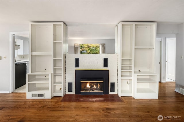 unfurnished living room featuring visible vents, wood finished floors, and a fireplace