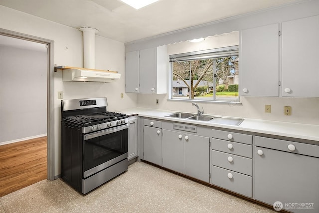 kitchen featuring a sink, gray cabinetry, light countertops, under cabinet range hood, and stainless steel gas range oven