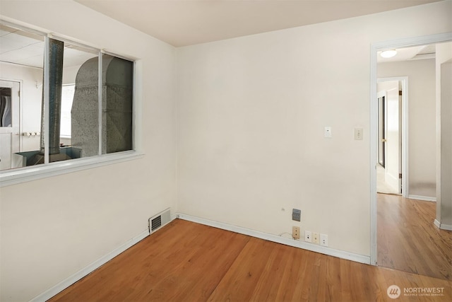 unfurnished room with visible vents, baseboards, and wood finished floors