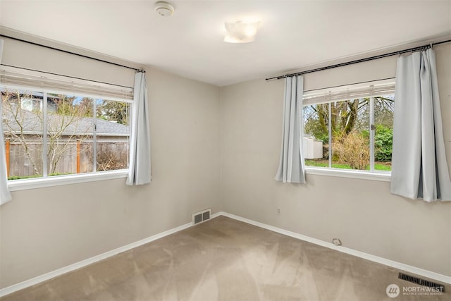 unfurnished room featuring a wealth of natural light, visible vents, and baseboards