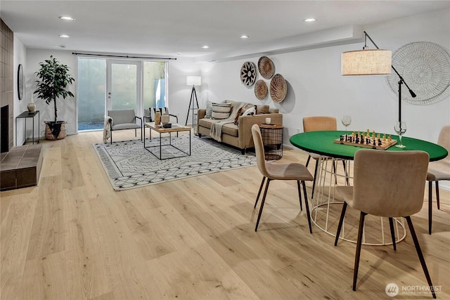 game room with a tiled fireplace and light wood-type flooring