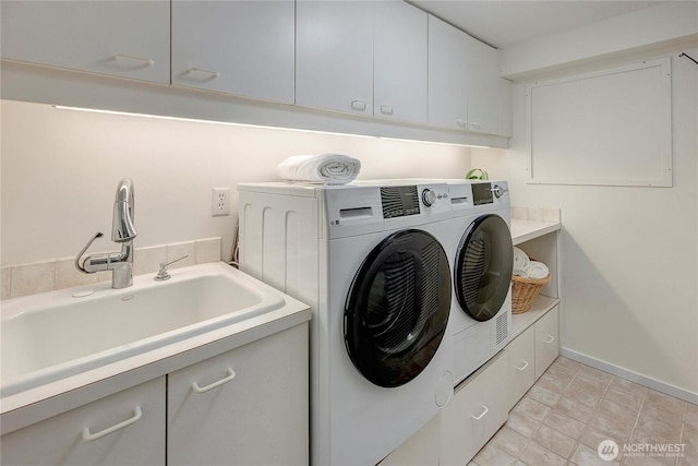 washroom with cabinets, washing machine and dryer, and sink