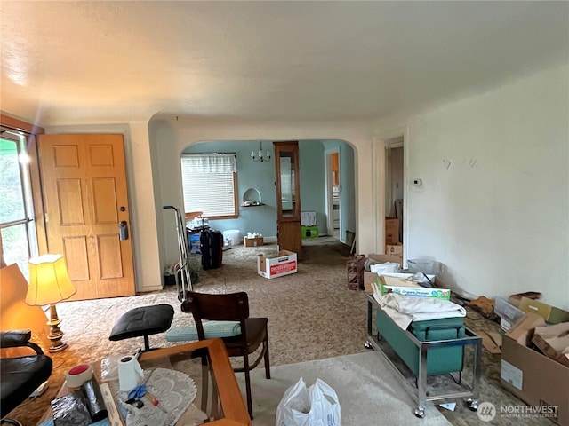 living room featuring arched walkways, an inviting chandelier, and light colored carpet