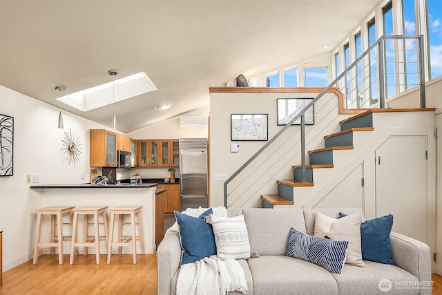 living room with light wood-type flooring, lofted ceiling with skylight, stairs, and an AC wall unit