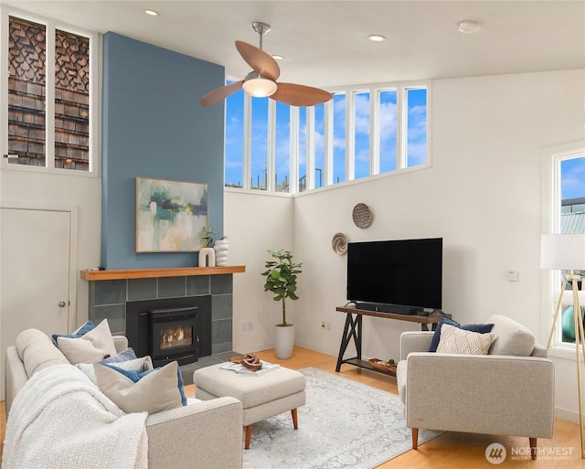 living room featuring recessed lighting, ceiling fan, wood finished floors, and a tile fireplace