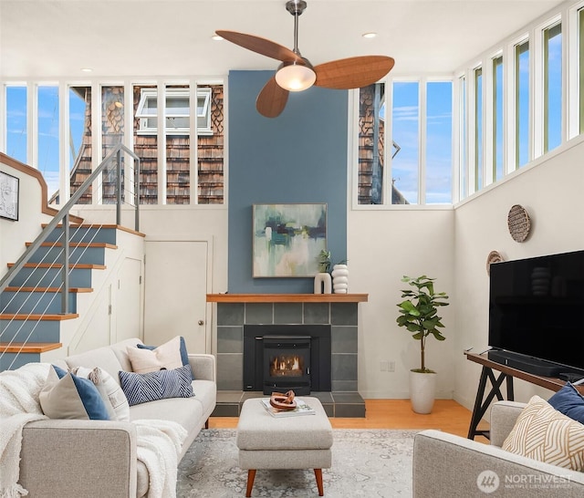 living area with recessed lighting, stairway, ceiling fan, wood finished floors, and a tile fireplace