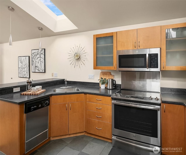 kitchen with dark countertops, stainless steel appliances, a peninsula, and a sink