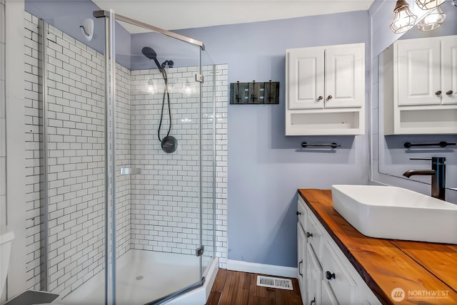 bathroom featuring visible vents, vanity, wood finished floors, and a shower stall