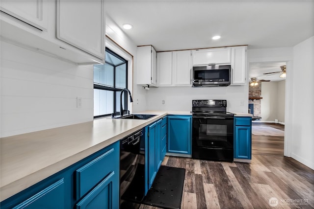 kitchen with white cabinetry, black appliances, blue cabinets, and a sink