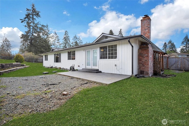 rear view of house with entry steps, fence, a yard, a chimney, and a patio area