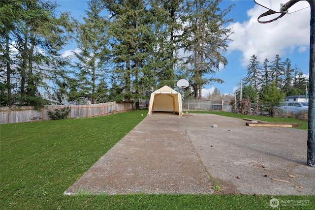 view of yard with basketball court and a fenced backyard