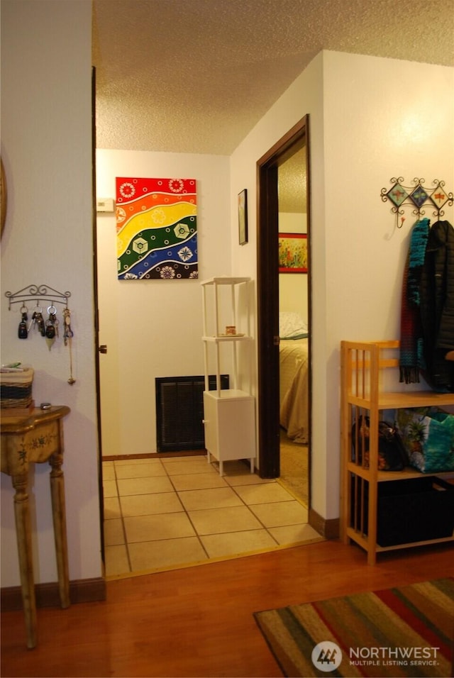 hall with wood finished floors, baseboards, and a textured ceiling