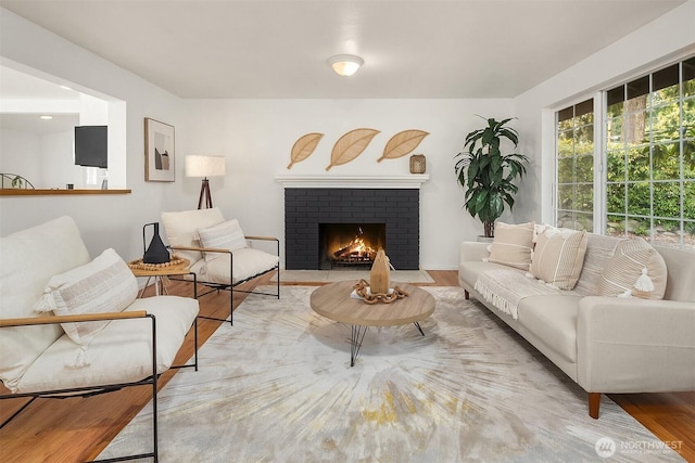 living room featuring a brick fireplace and light hardwood / wood-style flooring