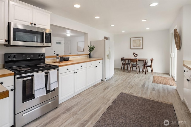 kitchen with stainless steel appliances, butcher block countertops, light hardwood / wood-style flooring, and white cabinets