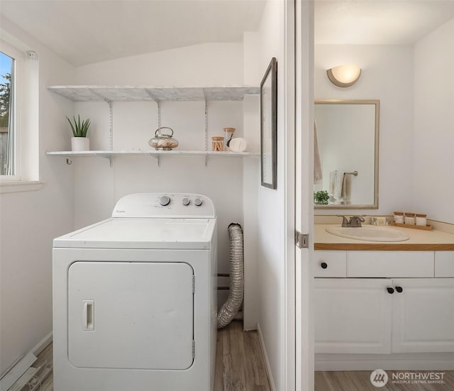 clothes washing area featuring washer / clothes dryer, sink, and light wood-type flooring