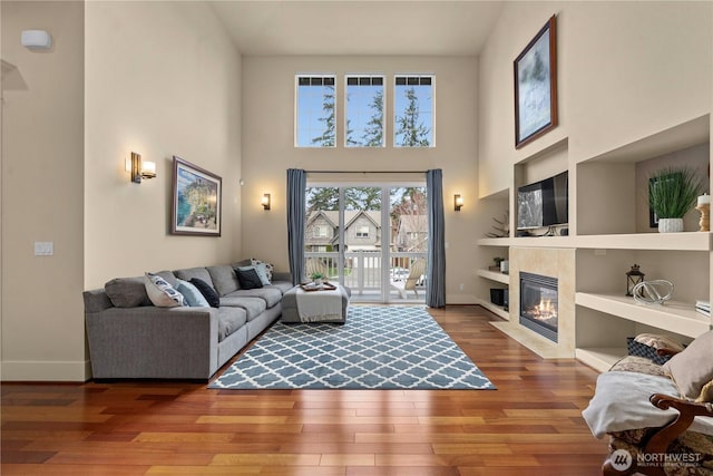 living room with a fireplace, built in features, wood finished floors, and baseboards