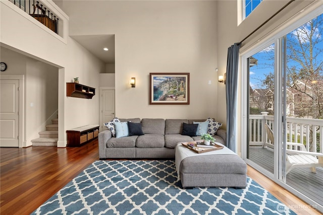 living area with a high ceiling, wood finished floors, and stairs