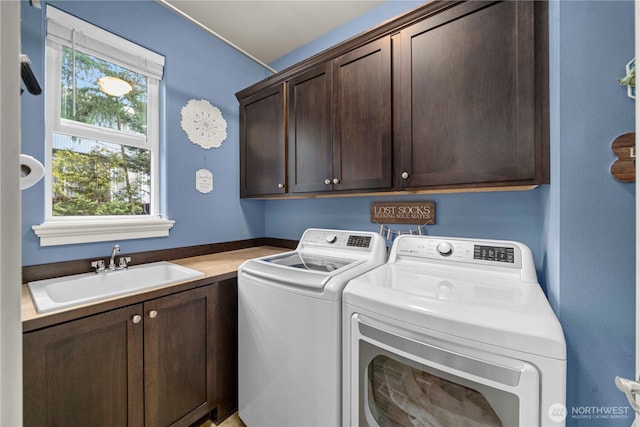 clothes washing area featuring a sink, cabinet space, and washing machine and clothes dryer