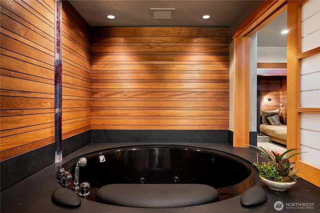 bathroom featuring wooden walls and a bath