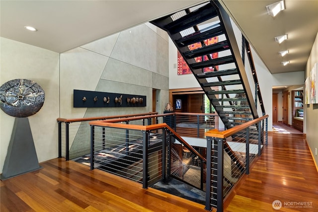 stairway with hardwood / wood-style flooring and a towering ceiling