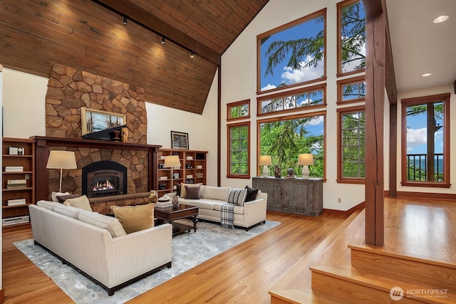 living room featuring high vaulted ceiling, a fireplace, wood-type flooring, rail lighting, and wood ceiling