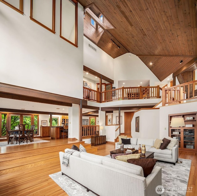 living room with wood ceiling, light hardwood / wood-style flooring, and a towering ceiling